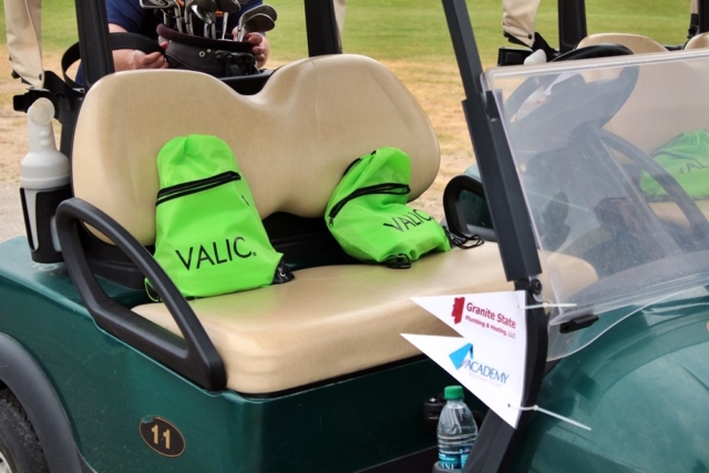 Valic goodie bags in golf cart with Granite State Plumbing & Heating, and Academy Roofing cart flags