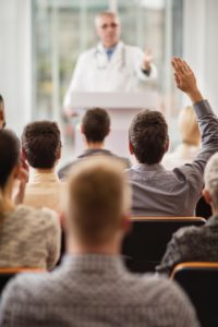 Back view of a man asking a question on seminar.